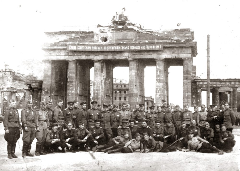 The Brandenburg Gate in ruins in May 1945 with a Soviet victory banner